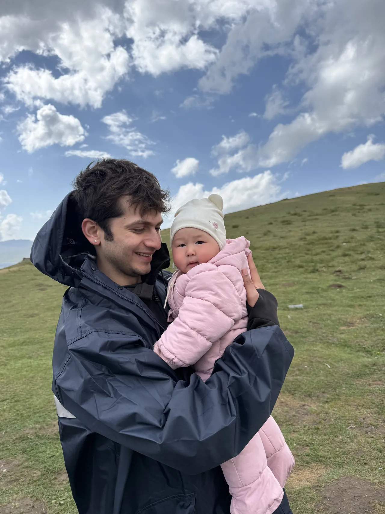 Monil holding a nomad family's baby at Song-Kul lake, Kyrgyzstan